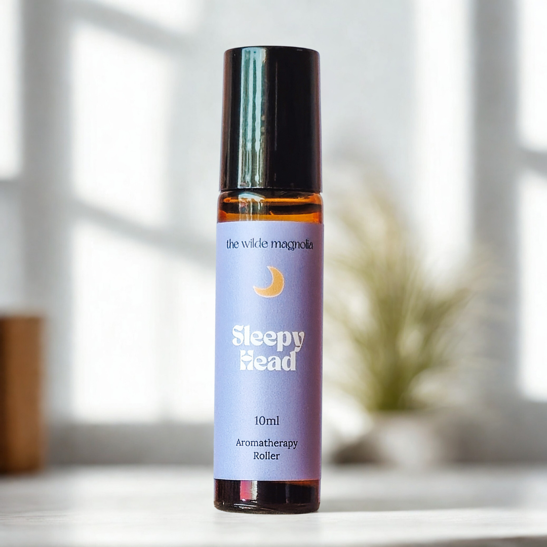 Aromatherapy roller bottle labeled 'Sleepy Head' on a blurred background