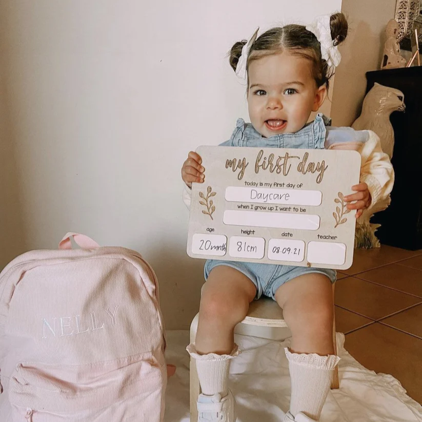 toddler girl holding a first day board