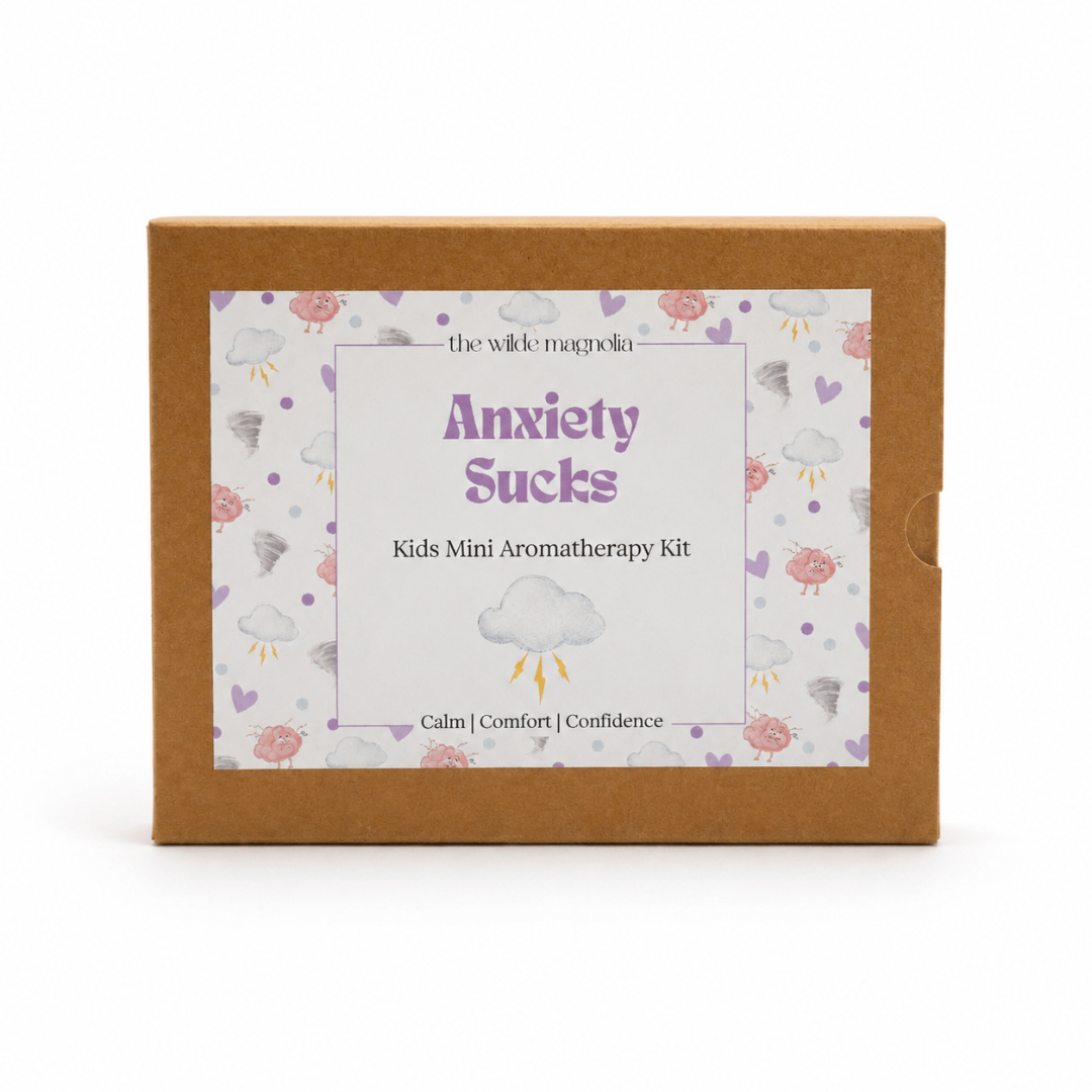 A square kraft paper box for 'Anxiety Sucks Kids Mini Aromatherapy Kit' by 'the wilde magnolia', featuring a white label with purple text and a cloud pattern on a white background.