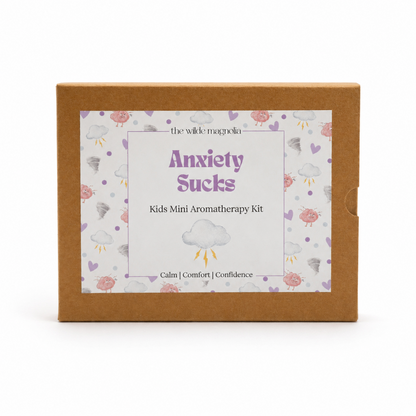 A square kraft paper box for 'Anxiety Sucks Kids Mini Aromatherapy Kit' by 'the wilde magnolia', featuring a white label with purple text and a cloud pattern on a white background.
