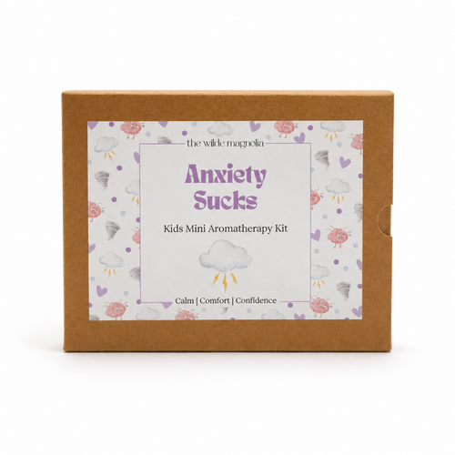 A square kraft paper box for 'Anxiety Sucks Kids Mini Aromatherapy Kit' by 'the wilde magnolia', featuring a white label with purple text and a cloud pattern on a white background.