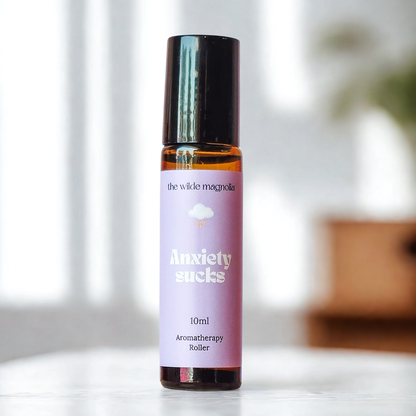 Aromatherapy roller bottle labeled 'Anxiety Sucks' on a blurred background