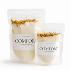 Two stand-up pouches of COMFORT Coconut Milk Bath by The Wilde Magnolia, one 125g and one 50g, shown on a clean white background.