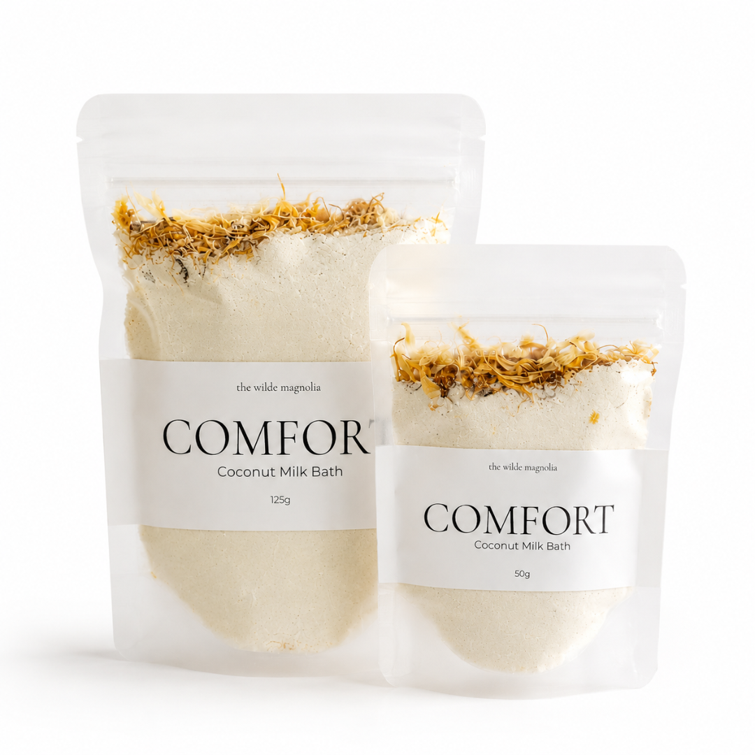 Two stand-up pouches of COMFORT Coconut Milk Bath by The Wilde Magnolia, one 125g and one 50g, shown on a clean white background.