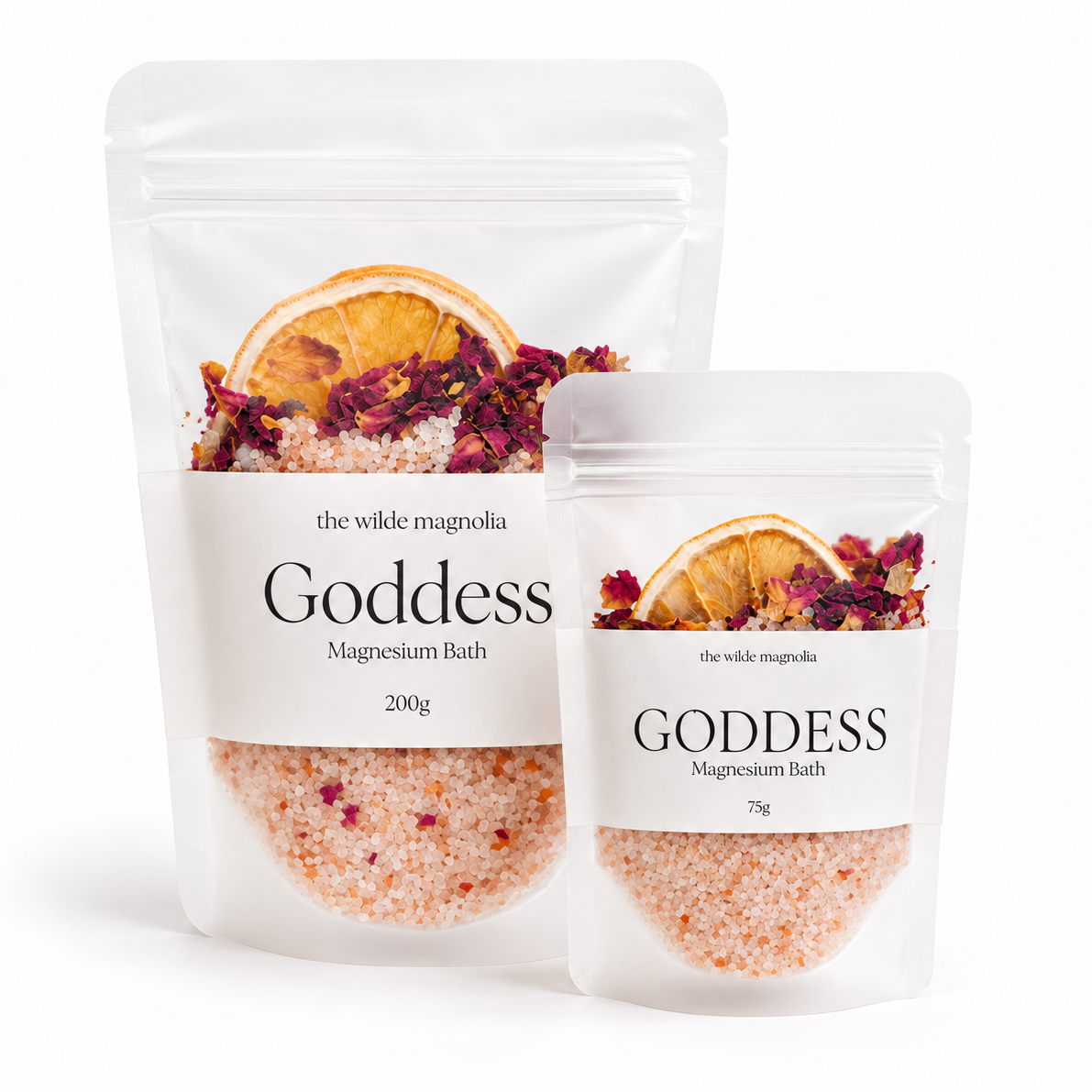 Two stand-up pouches of Goddess Magnesium Bath by The Wild Magnolia, one 200g and one 75g, shown on a clean white background. The clear packaging reveals pinkish-orange bath salts with dried orange slices and red rose petals printed on the label.