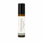 A 10ml amber glass rollerball bottle with a black cap, and a cream-colored label. The label features the brand name 'the wilde magnolia' and the scent name 'Harmony'.