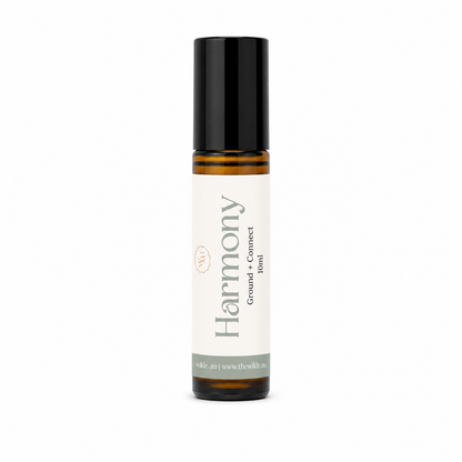 A 10ml amber glass rollerball bottle with a black cap, and a cream-colored label. The label features the brand name 'the wilde magnolia' and the scent name 'Harmony'.