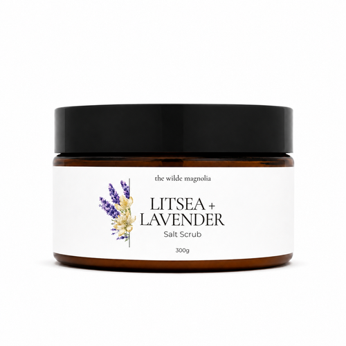 A 300g jar of 'Litsea + Lavender' salt scrub by 'The Wilde Magnolia'. The product is in an amber glass jar with a black lid and a white label featuring purple and yellow lavender illustrations.