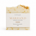 A rectangular bar of MARIGOLD unscented botanical cleansing soap by The Wilde Magnolia, featuring a cream-colored body with visible yellow calendula petals and a white paper label wrapped around the center.