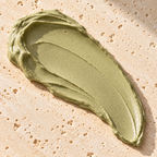 A creamy green smear of Matcha Glow clay mask on a stone background