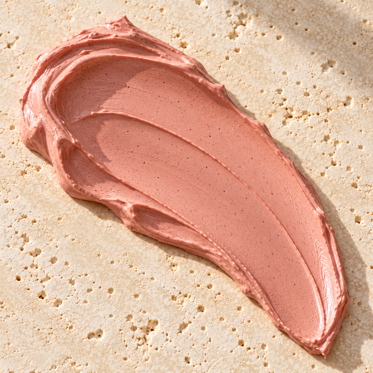 A smooth pink clay mask smeer on a stone background