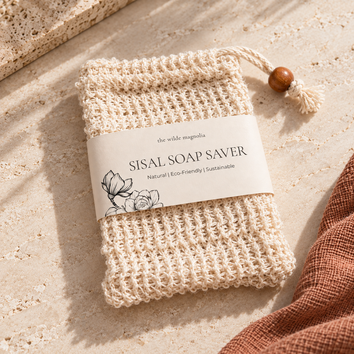 Soap Save bag made of natural Sisal fibre on a stone background with a terracotta coloured towel