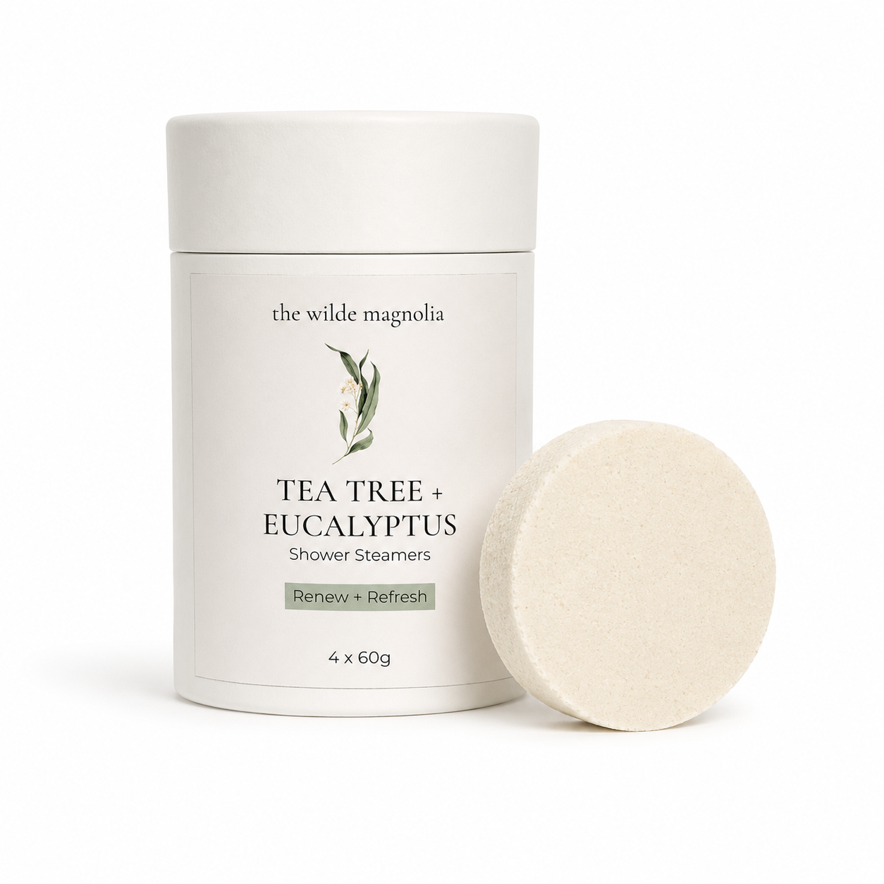 A white cylindrical container of 'the wilde magnolia' Tea Tree + Eucalyptus Shower Steamers, shown next to a single round, textured off-white steamers disc on a clean white background.