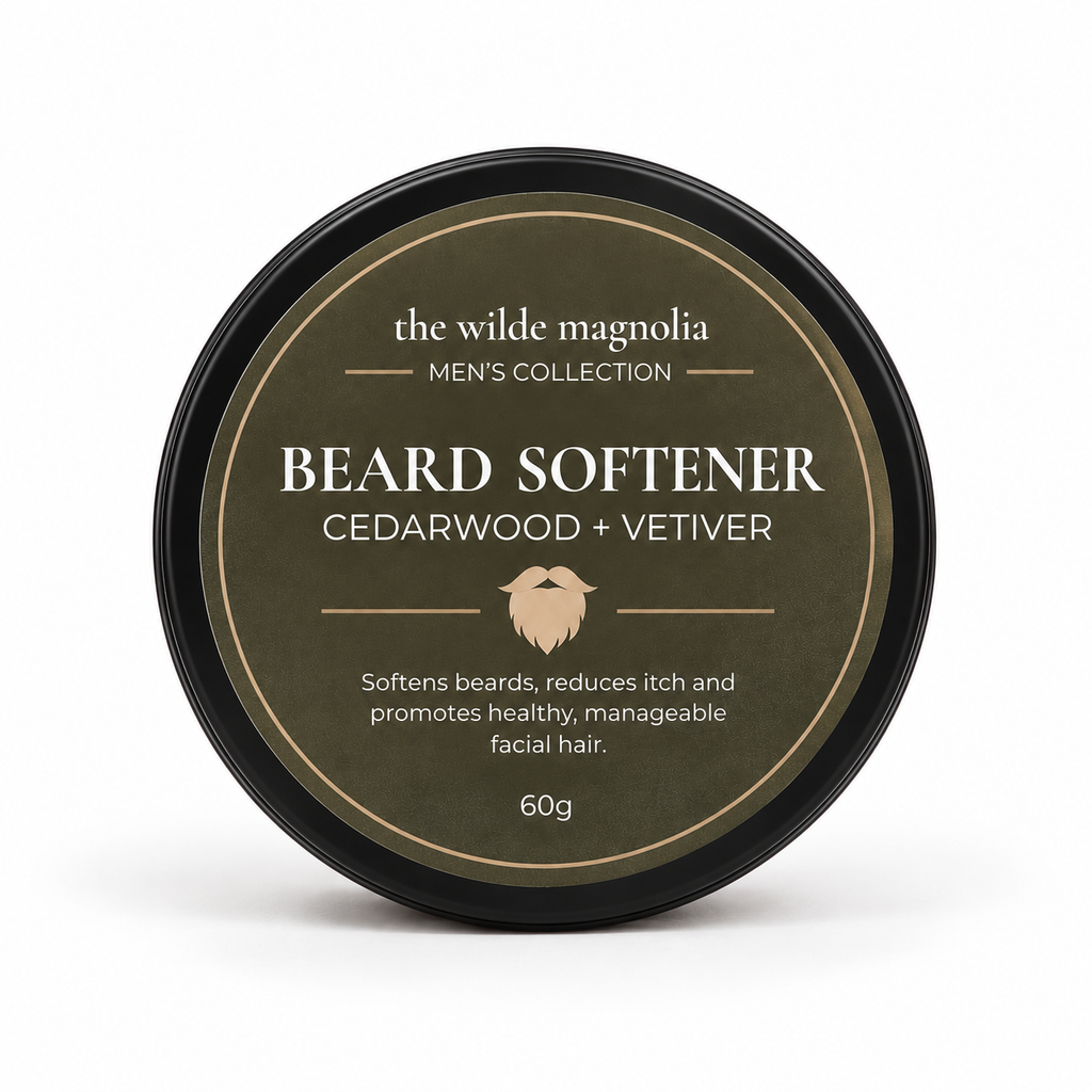 A round black tin with an olive-green label titled "Beard Softener, Cedarwood + Vetiver" by The Wilde Magnolia on a white background.