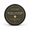 A round black tin with an olive-green label titled "Beard Softener, Cedarwood + Vetiver" by The Wilde Magnolia on a white background.