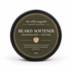 A round black tin with an olive-green label titled "Beard Softener, Cedarwood + Vetiver" by The Wilde Magnolia on a white background.